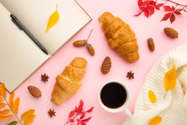 Sonbahar veya kış kompozisyonu. Bir fincan kahve, hediye, kurumuş sonbahar yaprakları, pembe arka planda kruvasan..