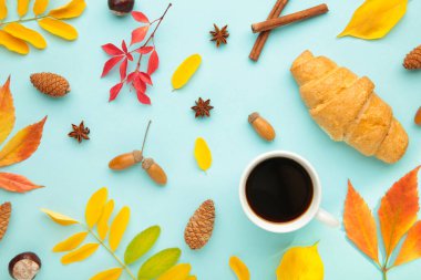 Sonbahar veya kış kompozisyonu. Bir fincan kahve, hediye, kurumuş sonbahar yaprakları, mavi arka planda kruvasan..
