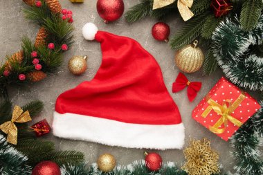 Gri arka planda Noel Baba şapkası olan Noel süsleri. Üst görünüm