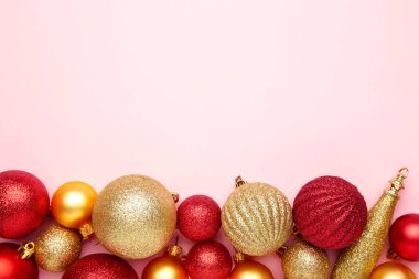 Pembe arka planda fotokopi alanı olan kırmızı ve altın noel topları. Üst görünüm