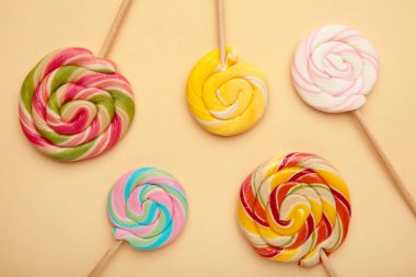 Bej arka planda renkli spiral lolipoplar. Üst görünüm