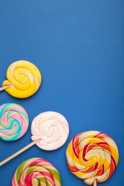 Mavi arka planda renkli spiral lolipoplar. Üst görünüm