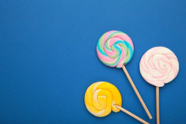 Mavi arka planda renkli spiral lolipoplar. Üst görünüm