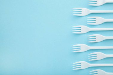 Mavi arka planda birçok plastik çatal var. Üst görünüm.