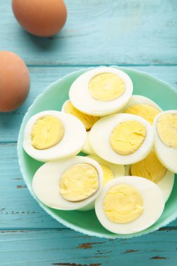 Mavi arka planda beyaz seramik tabakta haşlanmış yumurta. Üst görünüm