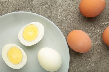 Gri arka planda beyaz seramik tabakta haşlanmış yumurta. Üst görünüm