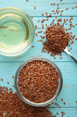 Mavi arka planda keten tohumu ve yağ kasesinde. Dikey fotoğraf. Üst görünüm