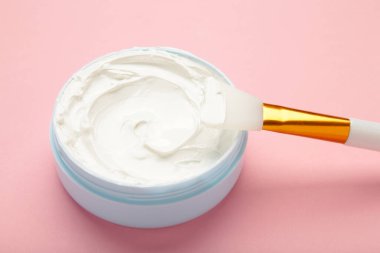 Pembe arka planda fırçalı bir kasede kozmetik maske. Üst görünüm