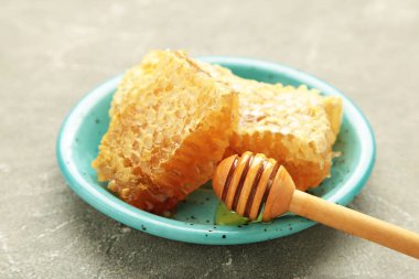 Tatlı bal, gri beton arka planda mavi plaka ve taraklar. Üst görünüm