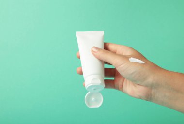 Nane arkaplanda boş beyaz plastik bir tüp tutuyor. Kozmetik güzellik ürünü markalaşma modeli.