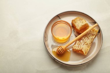 Bir kase tatlı bal, dippers ve hafif arka planda tabakta tarak. Üst görünüm