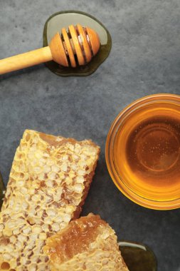 Bir kase tatlı bal, kepçeler ve siyah tabakta taraklar. Üst görünüm