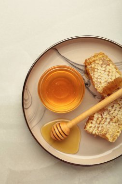 Bir kase tatlı bal, dippers ve hafif arka planda tabakta tarak. Üst görünüm