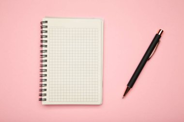 Pembe arka planda siyah kalem ve defterin en üst görüntüsü. Üst görünüm