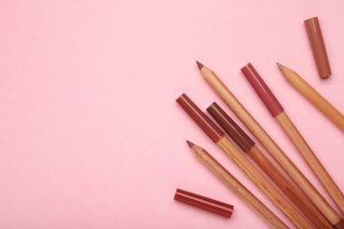 Pembe arka planda farklı dudak kalemleri. Kozmetik ürünü. en üstteki görünüm