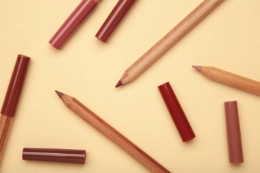 Bej arka planda farklı dudak kalemleri. Kozmetik ürünü. en üstteki görünüm