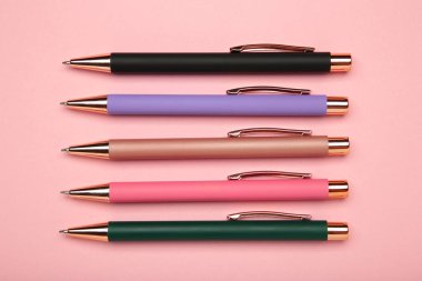 Pembe arka planda yeni renkli kalemler. Üst görünüm