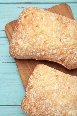 Ciabatta rustik ekmeği mavi arka planda kesim tahtasında. Üst görünüm.