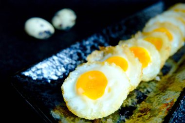 Siyah arka planda kızarmış bıldırcın yumurtası