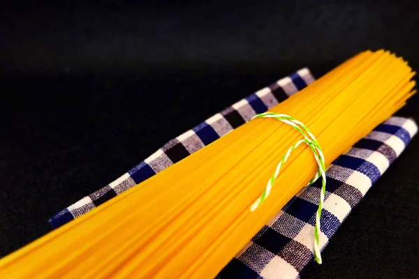 Un mazzo di spaghetti crudi con affusolato su fondo nero — Foto Stock
