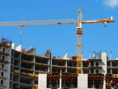 Mavi gökyüzüne karşı inşaat halindeki vinç ve beton bina. İnşaat alanı.