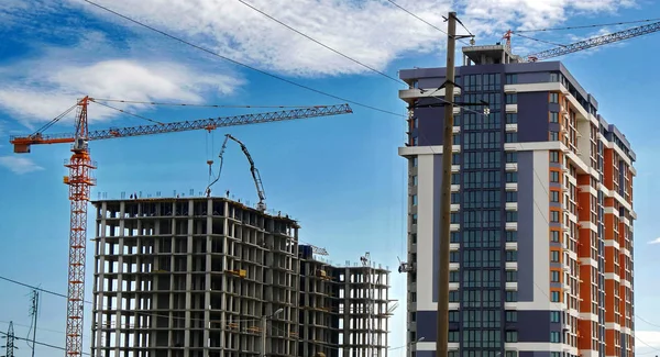 Mavi gökyüzüne karşı inşaat halindeki vinç ve beton bina. İnşaat alanı.