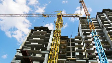 Mavi gökyüzüne karşı iki vinç. İnşaat alanı.