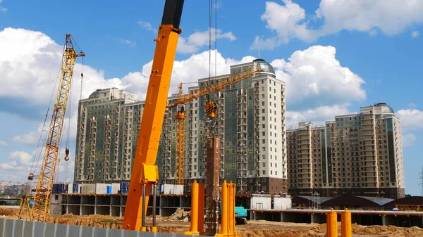 İnşaat alanında. Bina inşaat altında yakınındaki vinçler. İnşaat sahasında işçiler.