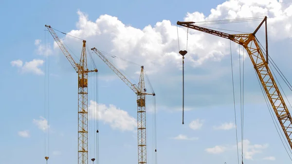 Mavi gökyüzü karşı üç İnşaat vinçleri.