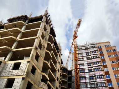 Vinç kaldırma ve inşaat faaliyetleri. İnşaat alanı. İki binanın arka planında vinç inşa ediliyor..