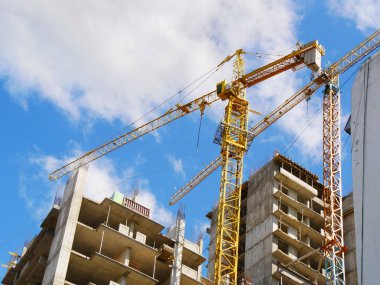 İnşaat alanı. Mavi gökyüzüne karşı iki kule vinci ve iki bina