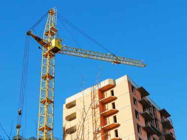 Bina yakınındaki vinç. Kırmızı tuğla bina inşaat altında. İnşaat alanı.