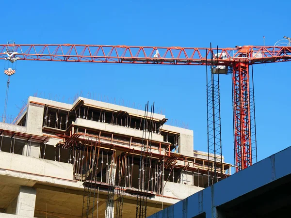 Red crane near building under construction. Construction site.