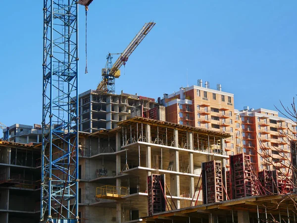 Construction site background. Unfinished building site. Industrial cranes near concrete unfinished buildings.