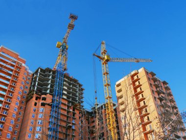 Çok katlı kırmızı tuğla ev inşaatı. Ticari İnşaat. Yapım aşamasında building yakınındaki iki Vinçler.