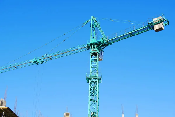 Crane. Huge crane. Hoisting crane against blue sky. Construction site.