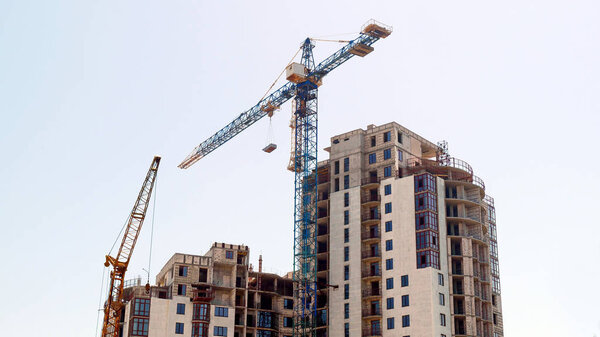 Two cranes near building under construction. Construction site.