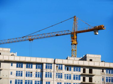 Beton bina inşaat altında. Vinç ve mavi gökyüzü karşı bina. İnşaat alanı.
