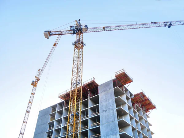 Dos grúas cerca del edificio. Edificio de hormigón en construcción . — Foto de Stock