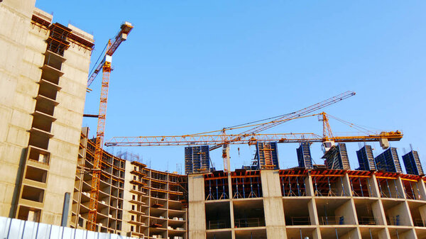 three building cranes on the background of a high-rise multi-sto