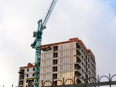 Modern bir yüksek katlı binanın inşaatı. Vinç cons yakın