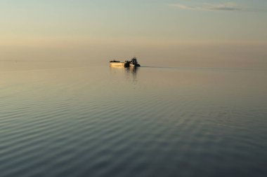 Günbatımı gölde altın gemide. Batan güneşin göl teknede aydınlatır. Ufuk çizgisi neredeyse görünmez