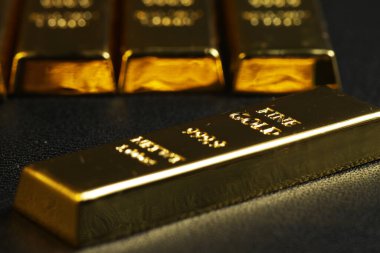 close up shot of stacked 999.9 pure gold bar ingot on a black background, represented the business, invesment and finance concept idea