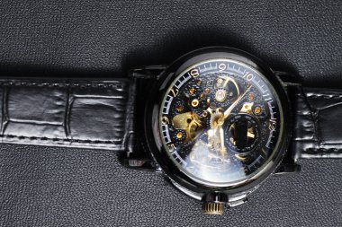 Siyah otomatik kol saati. Siyah deri arka planda transparan sekeleton arama dizaynı var.