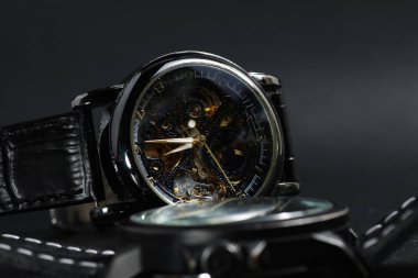 Siyah otomatik kol saati. Siyah deri arka planda transparan sekeleton arama dizaynı var.