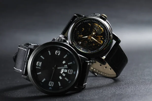 ブラックの自動巻き腕時計に透明なスケルトン文字盤のデザインとブラックのバッテリーはブラックレザーの背景に腕時計を操作 — ストック写真