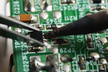Keskin uçlu cımbızla küçük bir elektronik bileşeni yakalama çekimini kapat