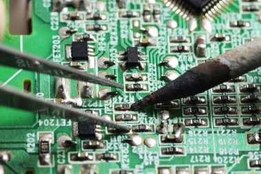 Keskin uçlu cımbızla küçük bir elektronik bileşeni yakalama çekimini kapat