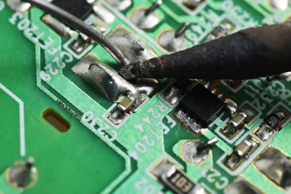 Close up shoot of soldering process SMD / surface mount component on a green Printed Circuit Board