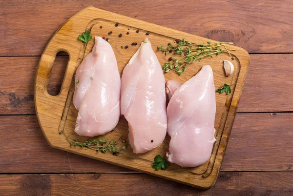 Kesme tahtası üzerinde baharatlar ile çiğ tavuk göğsü